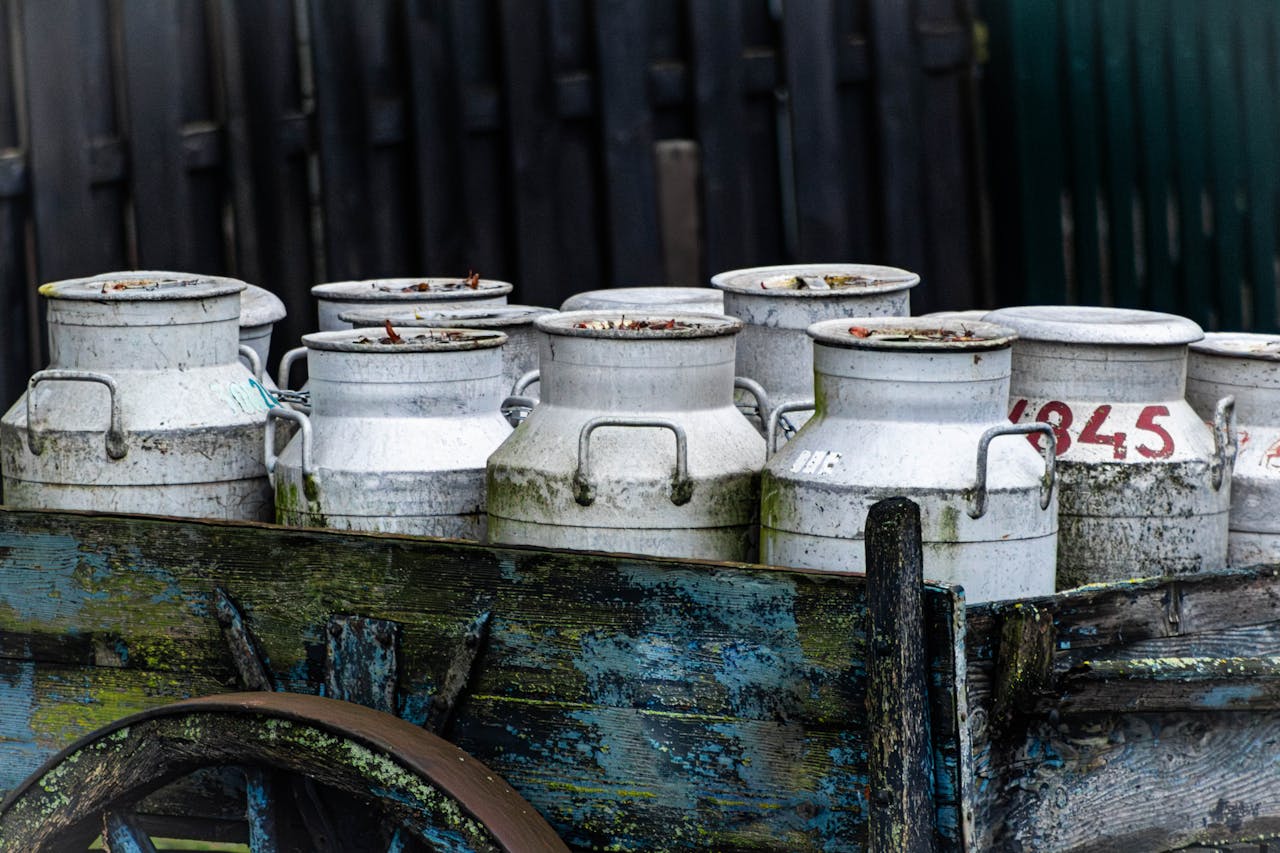 Mastering the First Impression: Your intriguing post title goes here Weathered milk cans rest on a vintage wooden cart, evoking rural nostalgia.