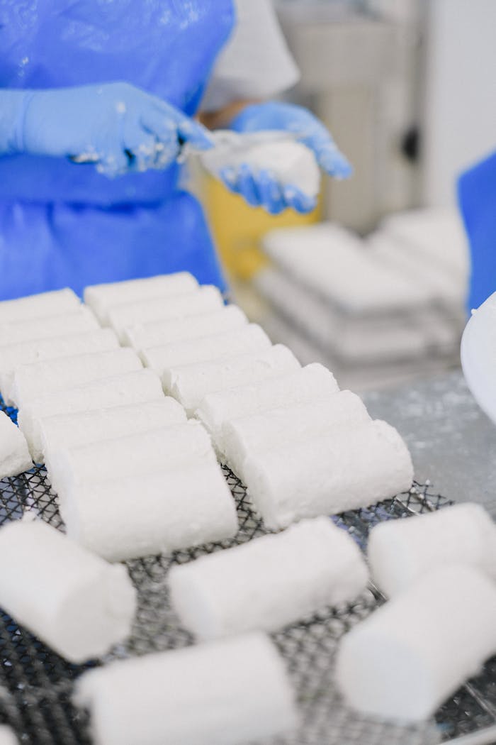 Close-up of cheese being processed by workers in an industrial setting.